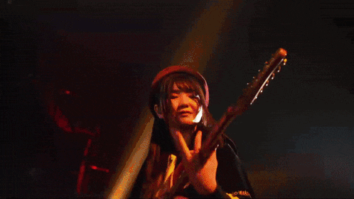 a woman in a hat is playing a guitar in a dark room