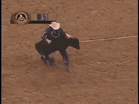 a cowboy is riding a bull in a rodeo arena with a scoreboard behind him that says 39
