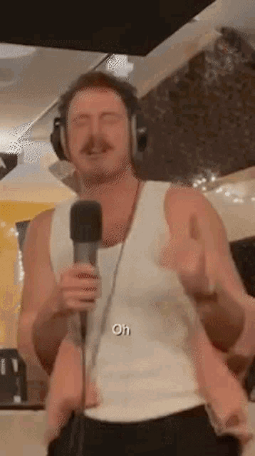 a man wearing headphones is holding a microphone and singing into it .
