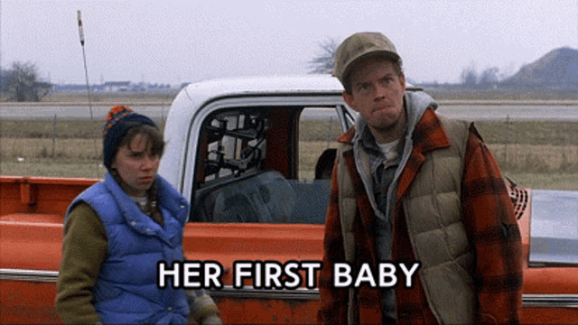 a man and a woman standing next to a truck with her first baby written on the bottom