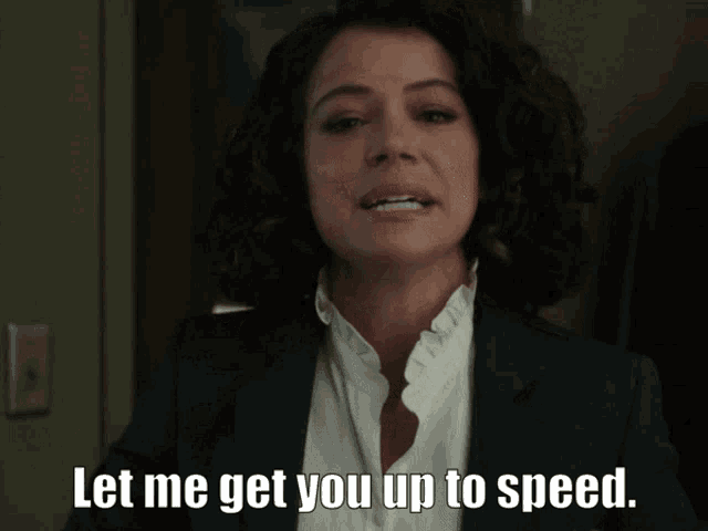 a woman in a suit and white shirt is saying let me get you up to speed
