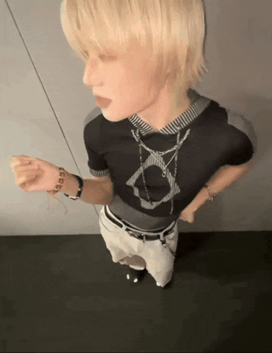 a man with blonde hair is wearing a black shirt that has a circle on it