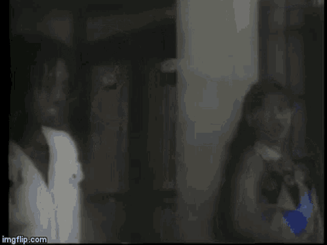 a man and a woman are standing next to each other in a room with a window .
