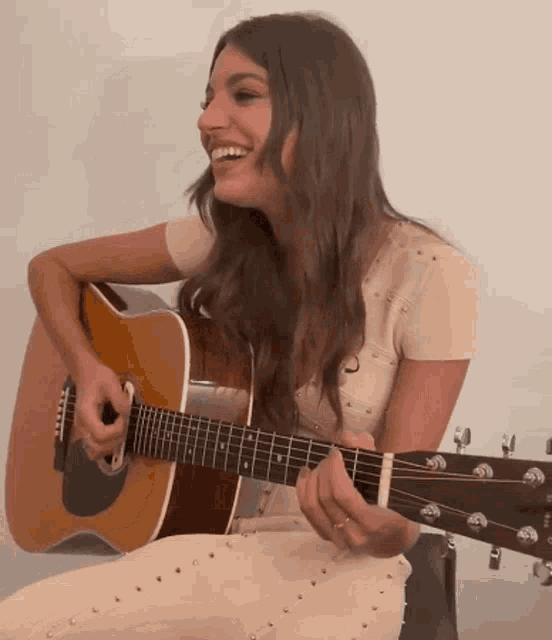 a woman in a white dress is playing a guitar