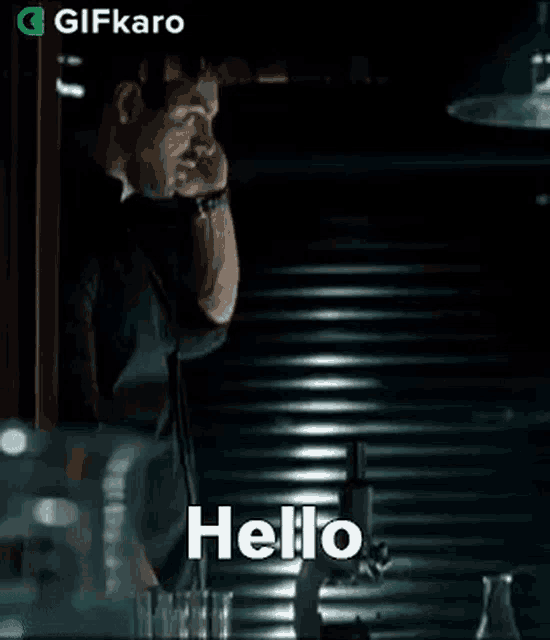 a man is talking on a cell phone in a dark room and the word hello is on the screen .