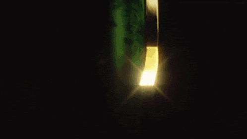 a close up of a green and gold object with a black background