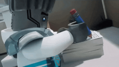 a lego robot is writing on a piece of paper with a pencil in his hand .