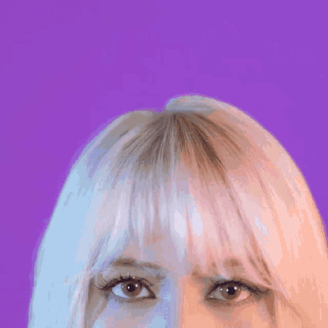 a close up of a woman 's face with blonde hair and a purple background