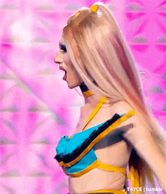 a woman with long blonde hair is wearing a blue and yellow top and choker .
