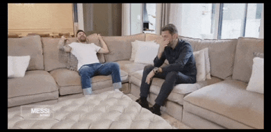 two men are sitting on a couch with messi written on the bottom right