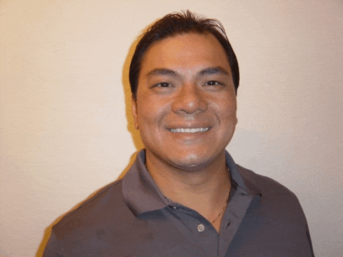 a man wearing a gray polo shirt smiles for the camera
