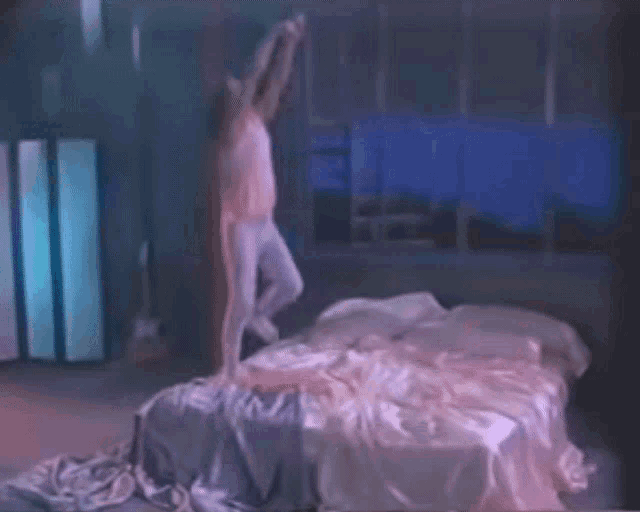 a man and a woman are laying on a bed in a dark room with a guitar in the background .