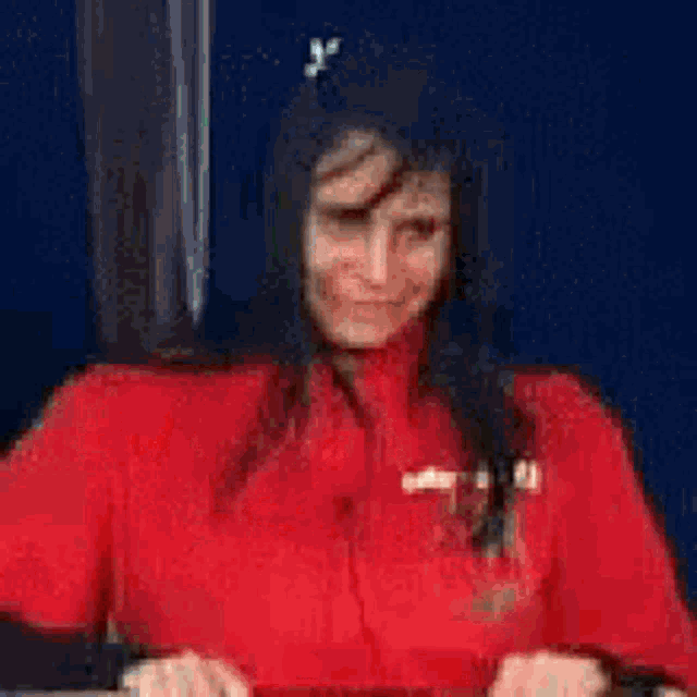 a woman in a red shirt is smiling and looking at the camera .
