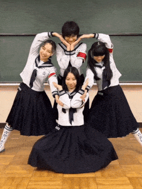 a group of girls in school uniforms are posing in front of a blackboard