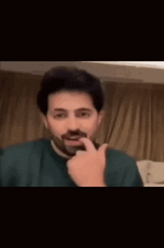 a man with a mustache is making a funny face and pointing at something .