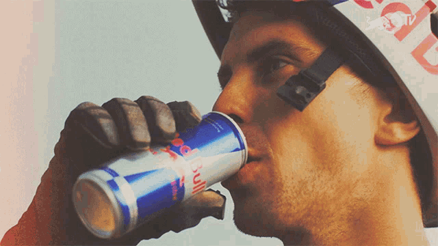 a man wearing a red bull helmet drinks a can of red bull