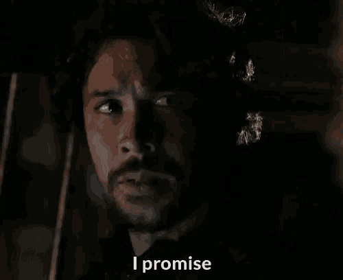 a man with a beard is saying i promise in a dark room