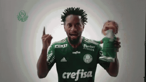 a man in a green crefisa jersey holds a can