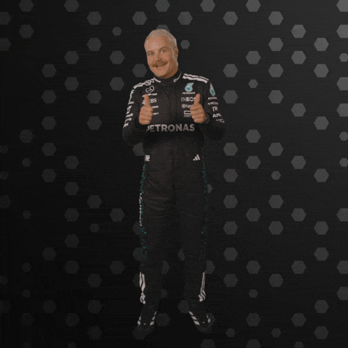 a man in a petronas suit stands in front of a dark background