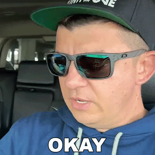 a man wearing sunglasses and a hat with the word okay on it
