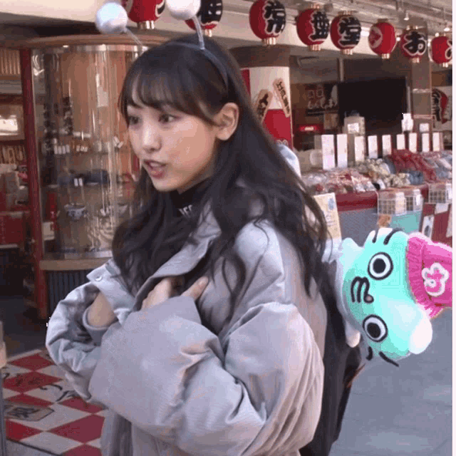 a woman wearing a headband and a backpack stands in front of a store with lanterns on the ceiling