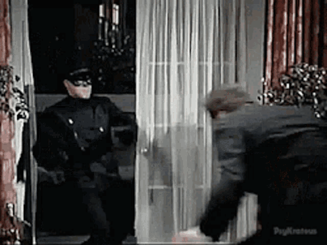 a man in a police uniform is standing in a doorway with a man in a suit behind him .