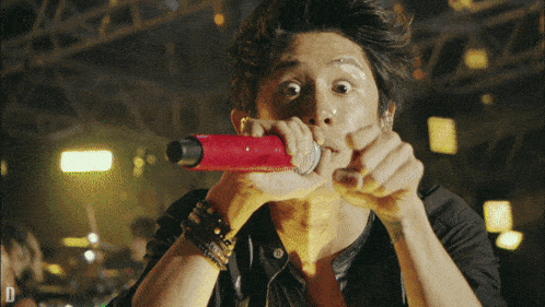 a man singing into a red microphone with the letter d visible in the corner