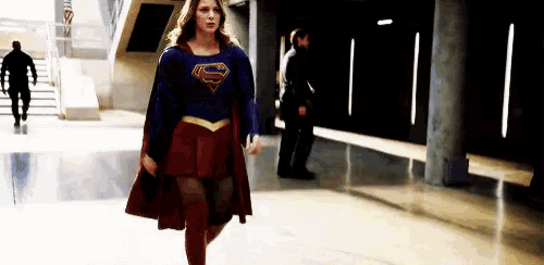 a woman in a superman costume walks through a hallway