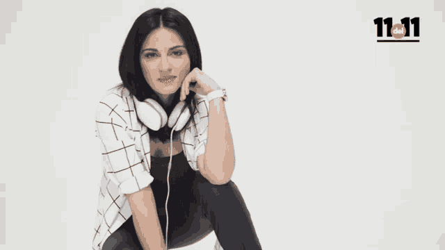 a woman wearing headphones is sitting in front of a white background with the number 11:11 on it
