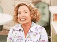 a woman in a floral shirt is laughing and smiling while sitting in a chair .