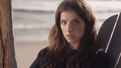 a close up of a woman sitting in a chair on the beach looking at the camera .