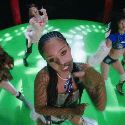 a group of young women are dancing on a green stage