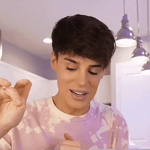 a young man wearing a pink tie dye shirt is eating something