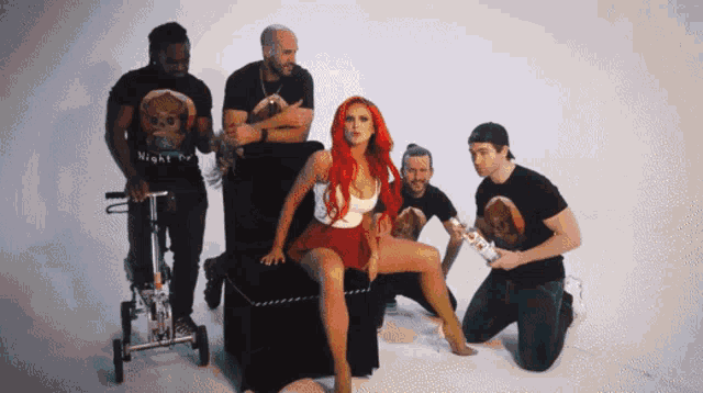 a woman with red hair is sitting in a chair surrounded by men in black shirts that say night fury