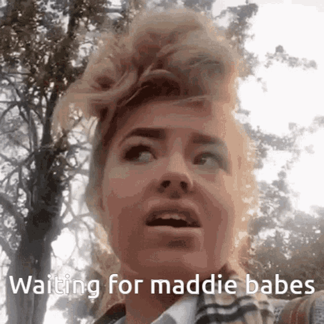 a woman with a plaid scarf around her neck says " waiting for maddie babes "
