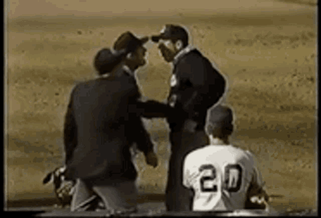 a baseball player with the number 20 on his back is talking to a referee on the field .