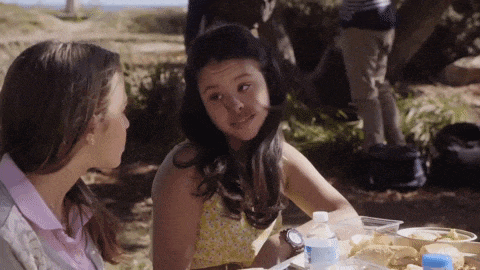 two girls are sitting at a picnic table talking to each other