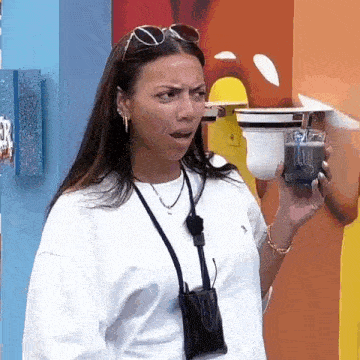 a woman is holding a cup of coffee in her hand and making a face .