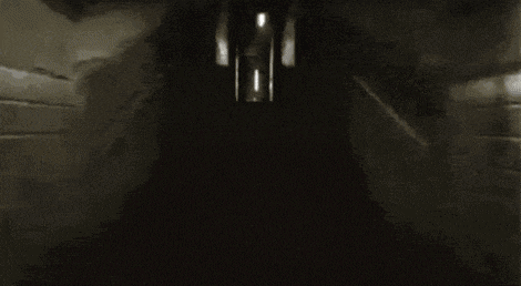 a dark hallway with a light coming out of the door