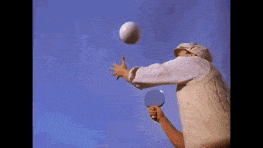 a man is playing ping pong with a balloon in his hand
