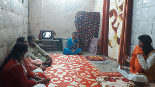 a group of women sit on a rug in a room