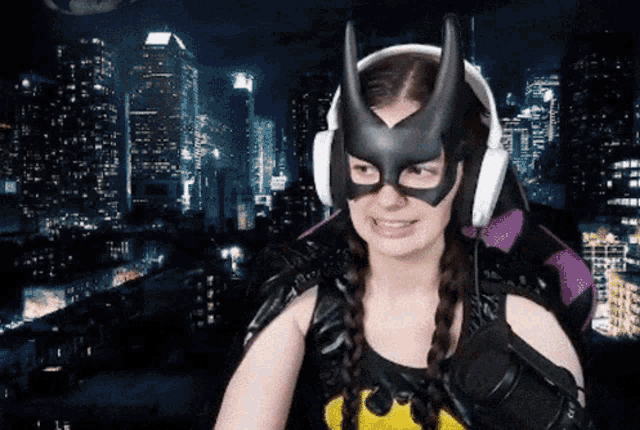 a woman wearing a batman mask and headphones is smiling