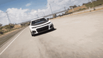 a white car is driving down a road in the desert