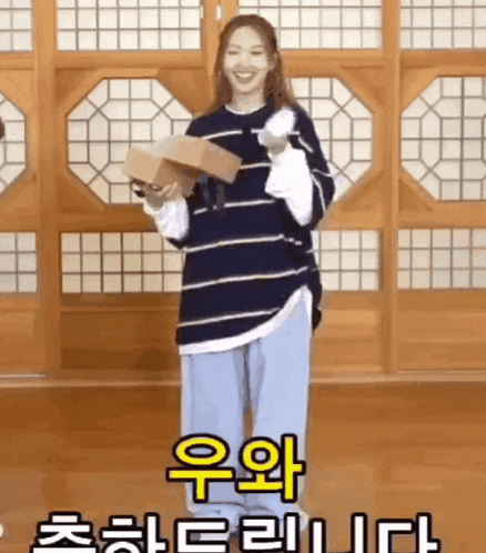 a woman in a striped shirt is holding a box in her hands .