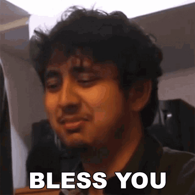 a man with curly hair is making a funny face and saying `` bless you '' .