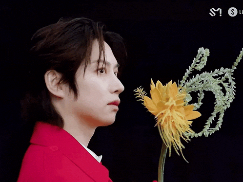 a man in a red suit holds a yellow flower