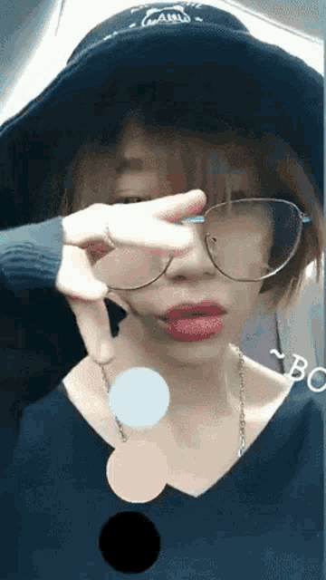 a woman wearing glasses and a hat has a circle in the middle of her face