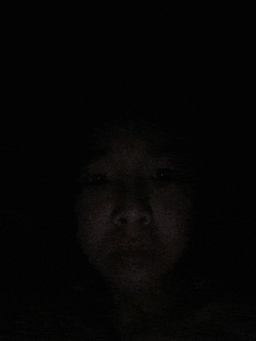 a person 's face is shown in the dark with their eyes closed