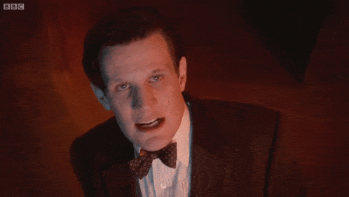 a man in a suit and bow tie is making a funny face in front of a screen that says bbc on it