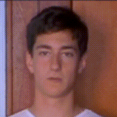 a close up of a young man 's face with a white shirt on